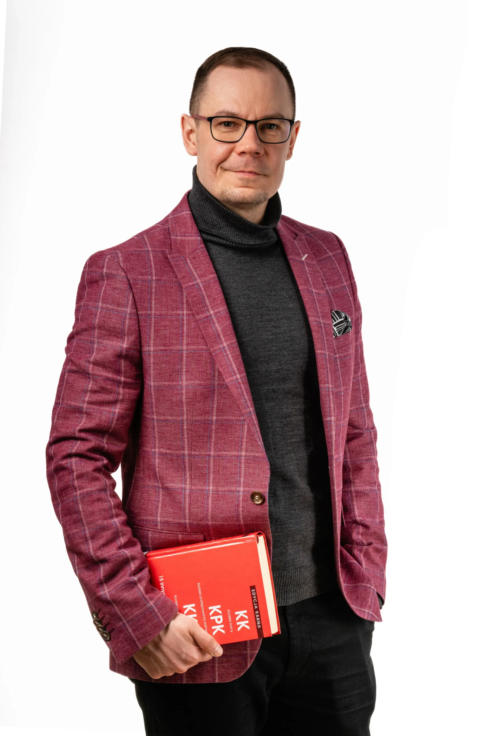 zdjęcie Radcy Prawnego Michała Pietrzaka z książką w ręku, ubrany jest w marynarkę